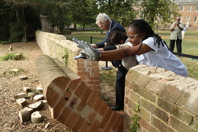 Hearth: Memorial to the Enslaved:  President Emeritus Taylor Reveley LL.D. ’18, W&M President Katherine A. Rowe and Jody Allen Ph.D. ’07 push down a large panel of the wall in the location where the memorial will be constructed.