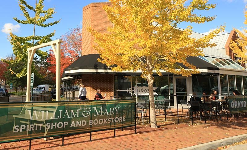 Front of the Bookstore with a brick patio and chairs, brightly colored fall foliage and William & Mary Spirit Shop and Bookstore printed on a sign